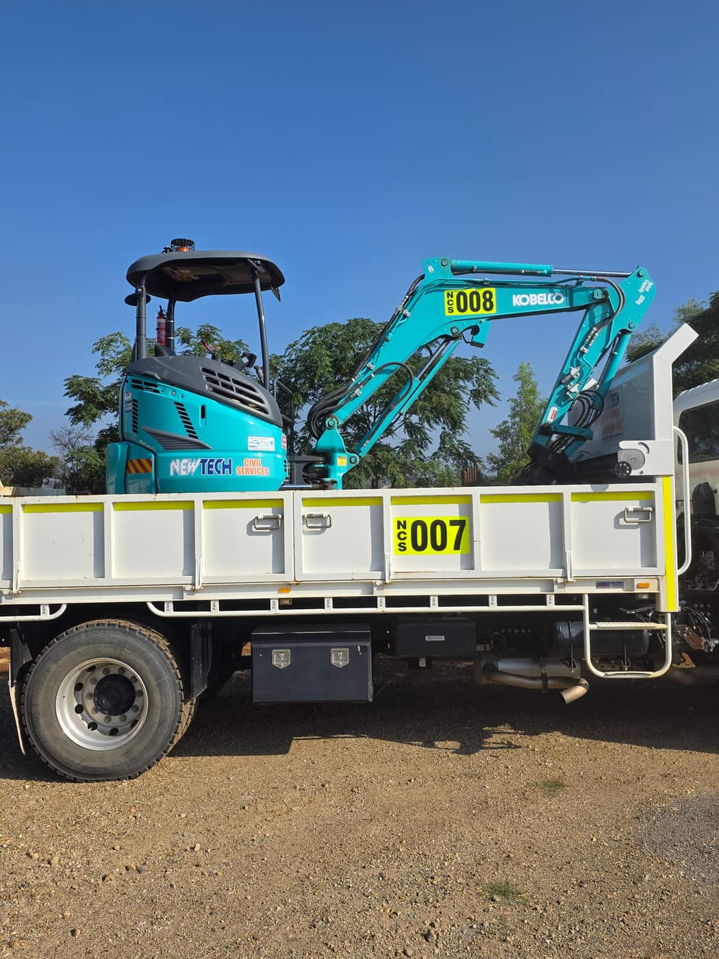 A Newtech mini excavator loaded on the tray of the company tipper